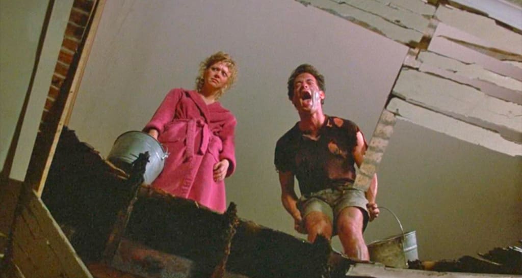 still image from "The Money Pit" with Tom Hanks laughing hysterically and Shelley Long looks like....Shelley Long.